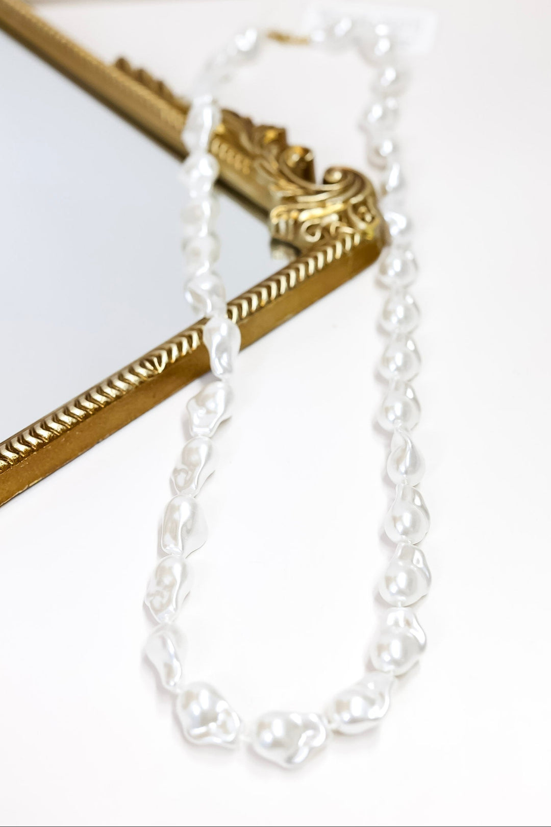 Gold and white pearl necklace on a white background