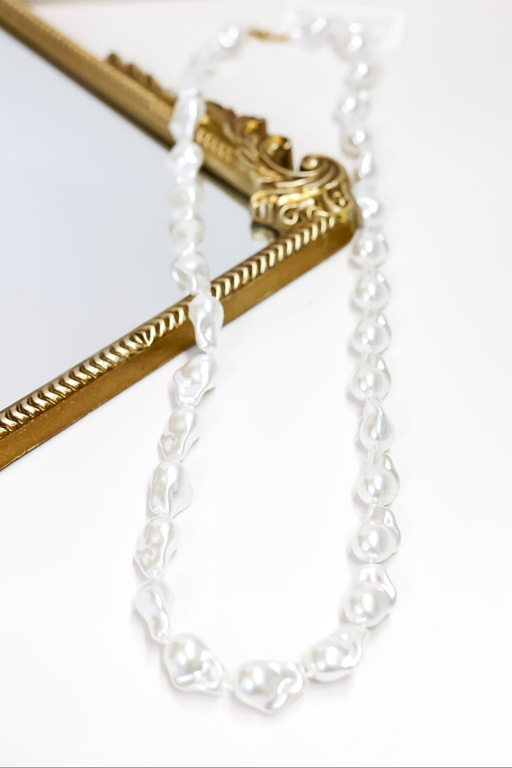 Gold and white pearl necklace on a white background