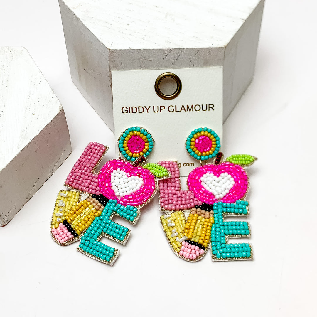 LOVE Beaded Earrings Teacher Themed in Multicolor. These earrings are on a white background and have white posts around them.
