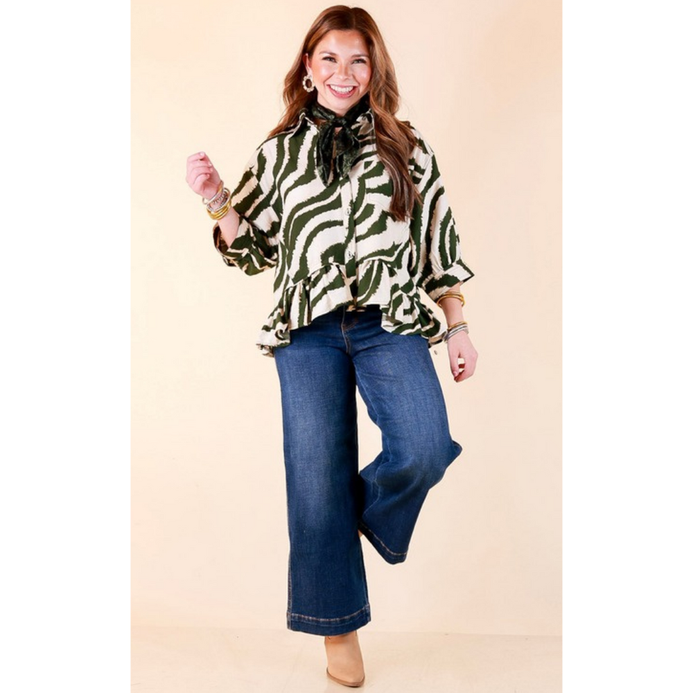Full length image of a woman wearing the Making Waves Zebra Print Ruffle Hem Button Up Top in Olive