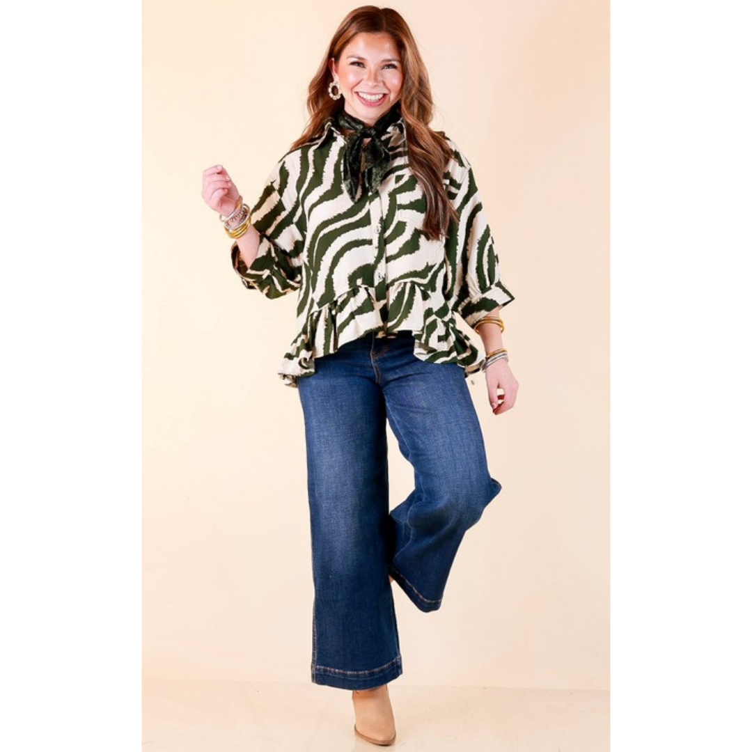 Full length image of a woman wearing the Making Waves Zebra Print Ruffle Hem Button Up Top in Olive