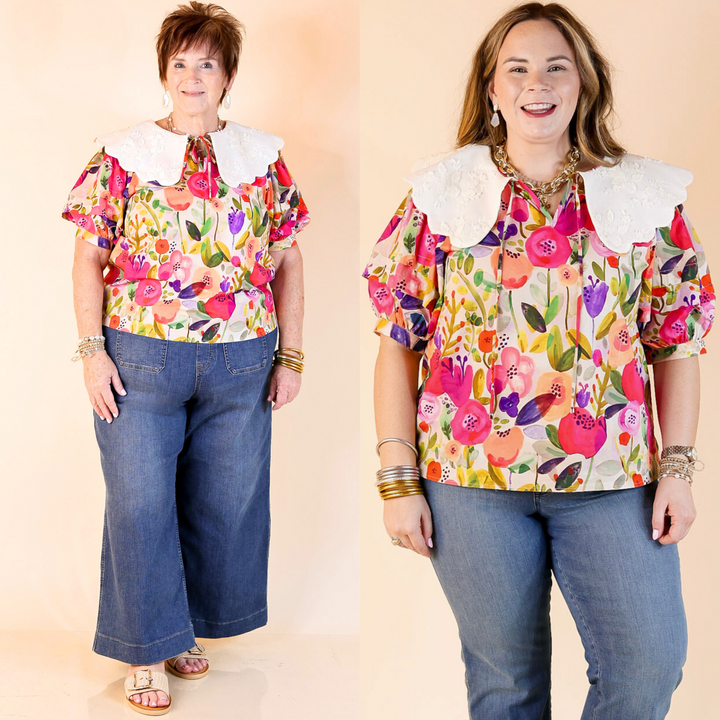 This top features a colorful floral print, short puff sleeves, a tie closure at the neckline, and a white peter pan collar with floral embroidery. Featuring a plus size model.