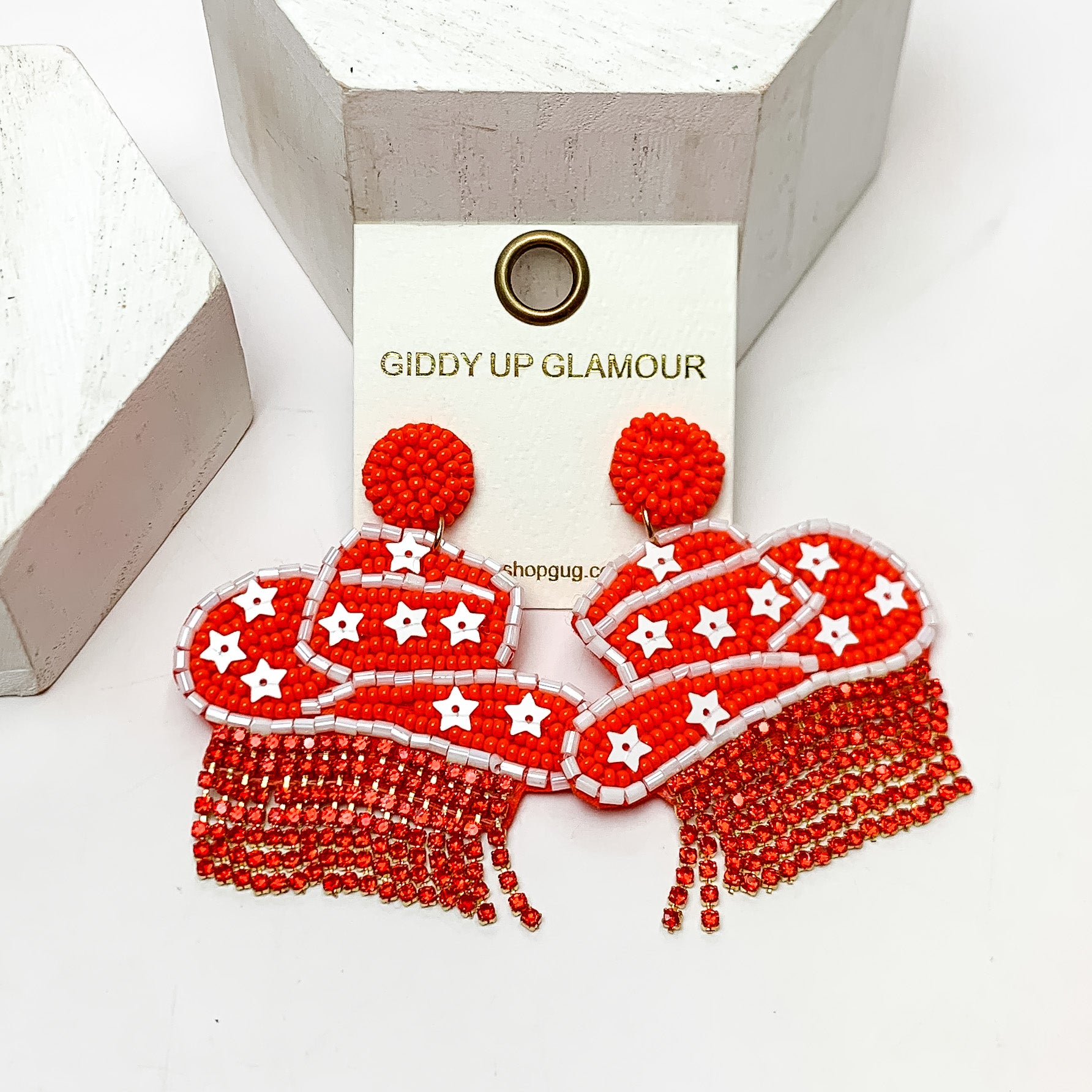 Gameday Beaded Cowboy Hat Earrings with White Crystal Fringe in Orange and White. These earrings are pictured on a white background with white posts behind them.