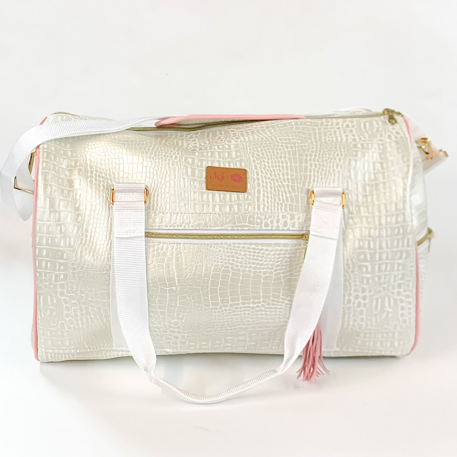 Pictured on a white background is a duffel bag with white straps in a pearl white gator print. This bag includes a zipper tassel, two short white straps, and a long white strap.