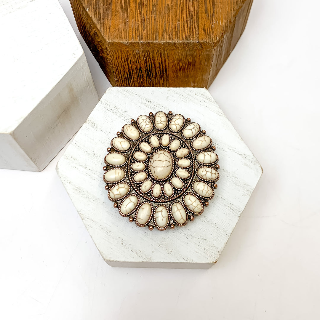 Copper Tone And Ivory Stone Circle Phone Grip. This phone grip is pictured on a white block with a white background behind it.