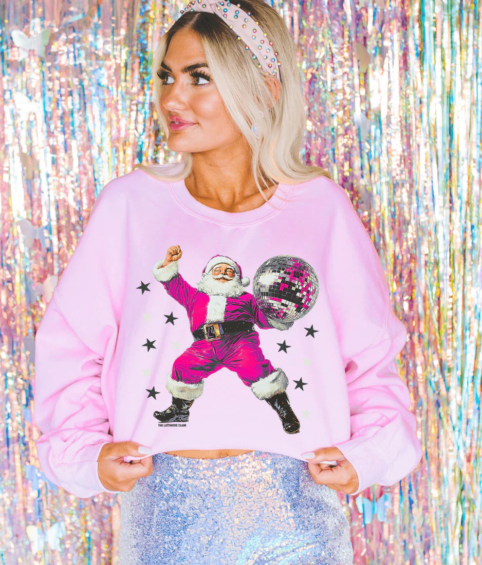 Person wearing a pink sweatshirt with a graphic of a dancing Santa Claus against a colorful, tinsel background.