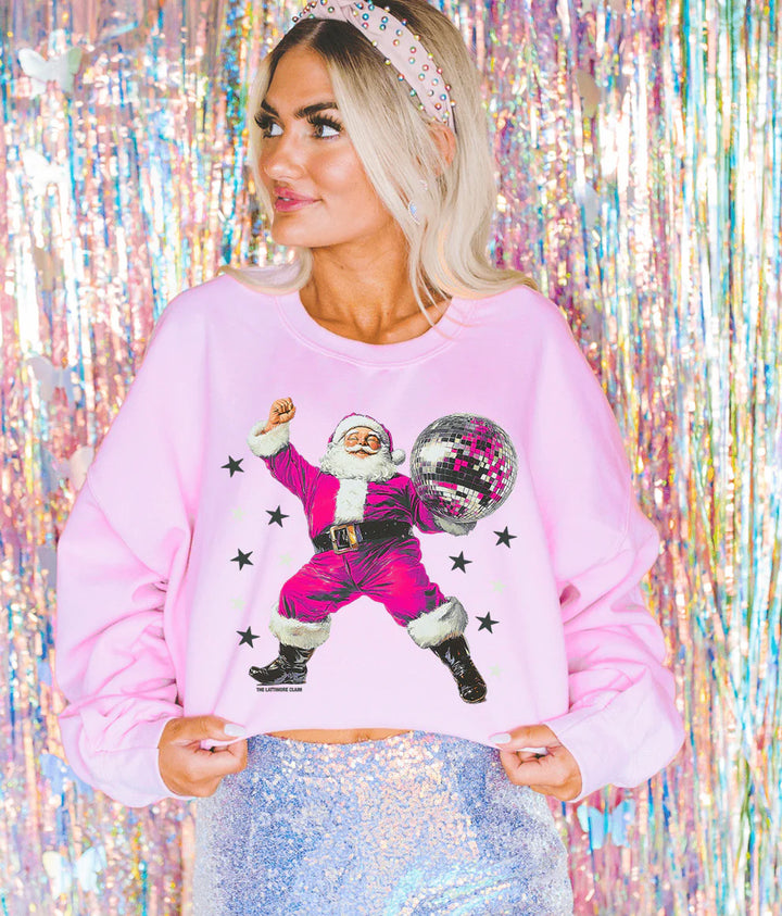 Person wearing a pink sweatshirt with a graphic of a dancing Santa Claus against a colorful, tinsel background.