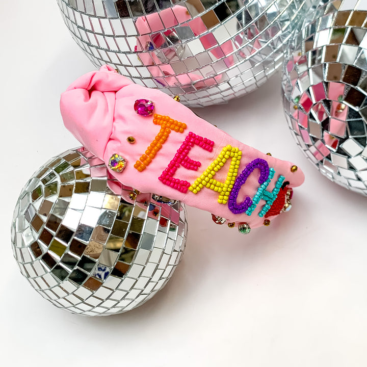 Beaded Multicolor Teacher Headband in Light Pink . This headband is pictured on a white background with disco balls next to the headband.