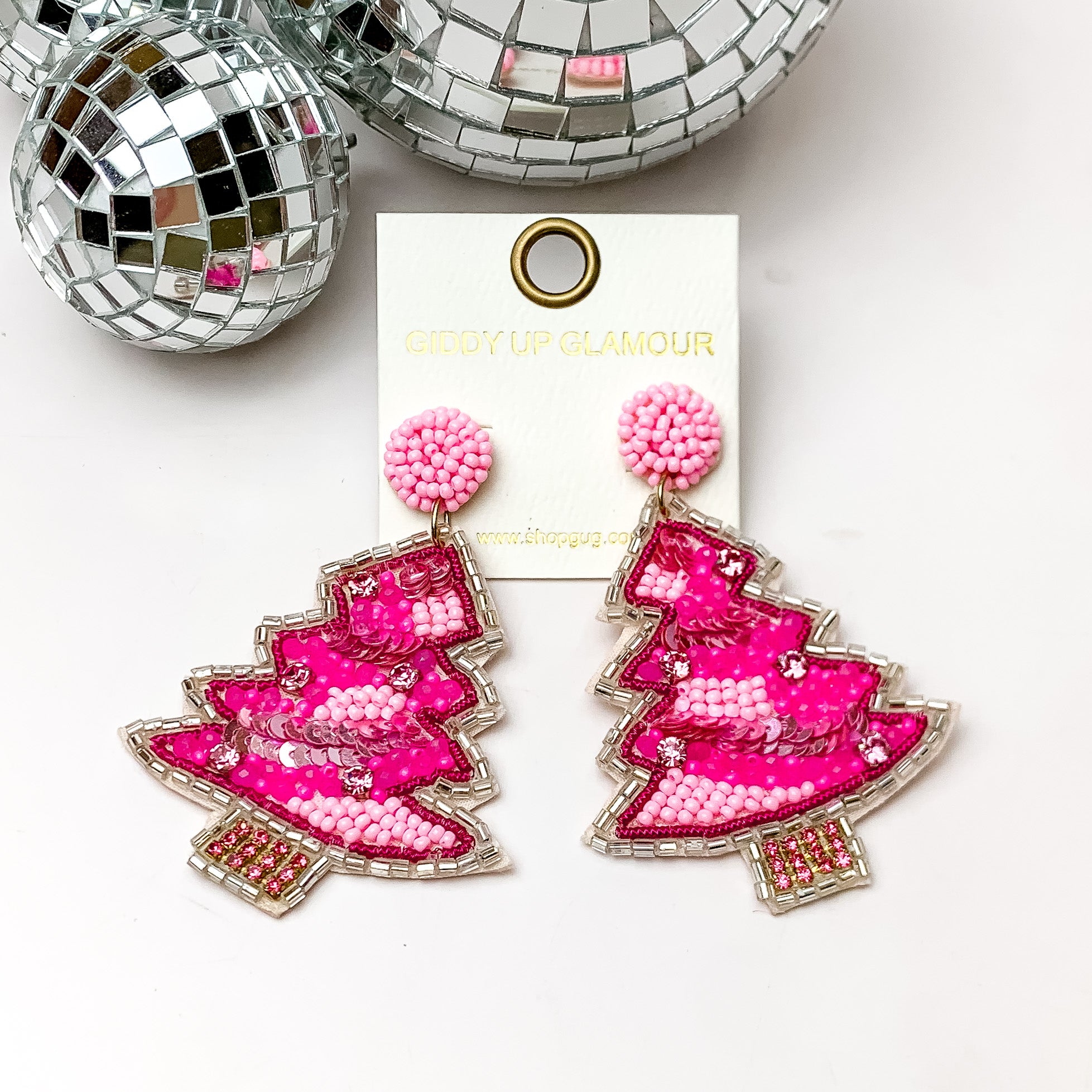 Pink mix beaded Christmas tree earrings with a beaded silver outline. These earrings are pictured on a white background with disco balls at the top. 