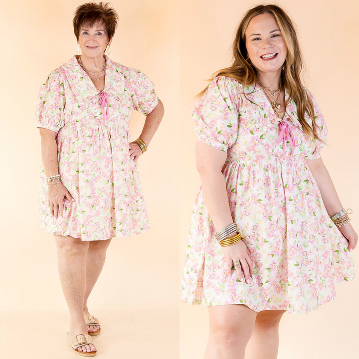short cream colored dress with pink floral print, a sailor collar, short puff sleeves, and a pink tie closure on the neckline. Featuring a plus size model, this dress comes in small through plus sizes.