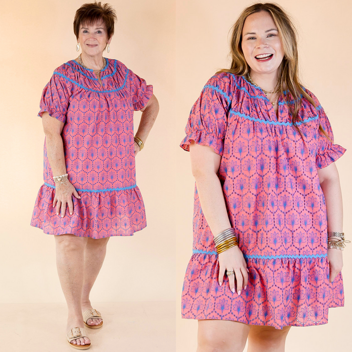 short pink dress with eyelet lace detail, short puff sleeves, v neckline, and blue rickrack detailing. Featuring a pus size model, this dress is available in size small through plus sizes.