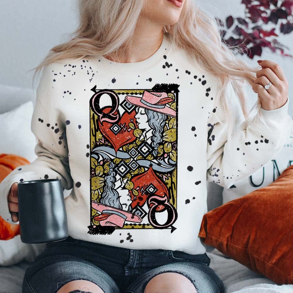 Model is wearing a white long sleeve sweatshirt that has a queen of hearts playing card on the front. The sweatshirt has black splatter paint detailing.