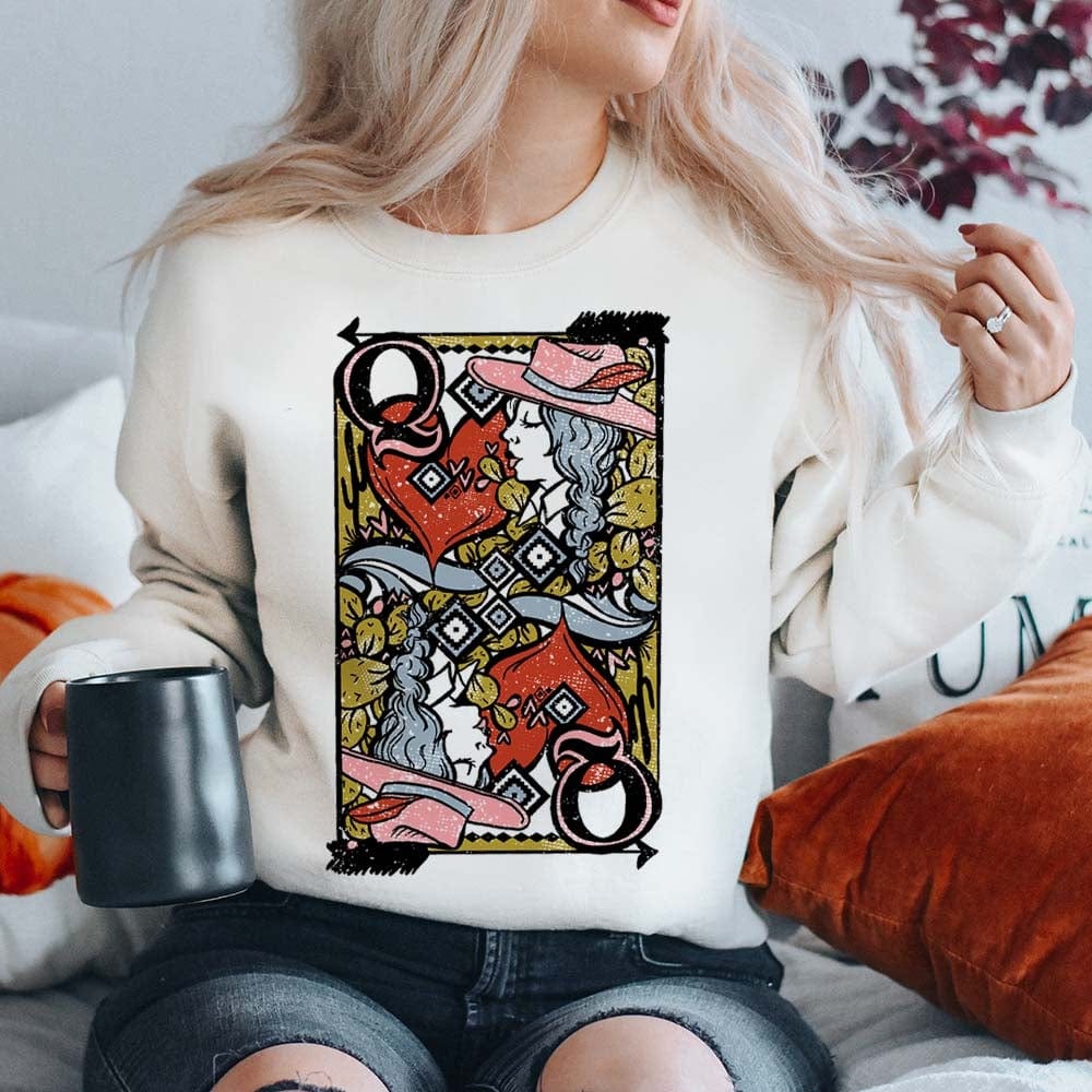 Model is wearing a white sweatshirt that has a Queen of Hearts playing card on the front. Model has it paired with distressed black jeans.
