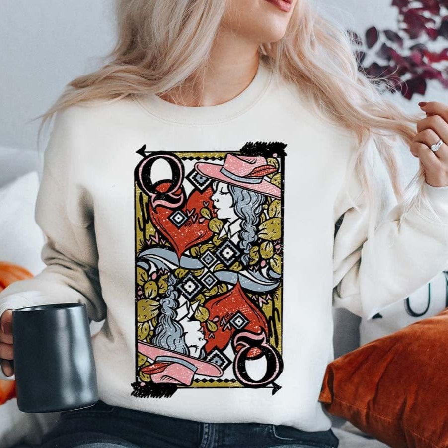 Model is wearing a white sweatshirt that has a Queen of Hearts playing card on the front. Model has it paired with distressed black jeans.