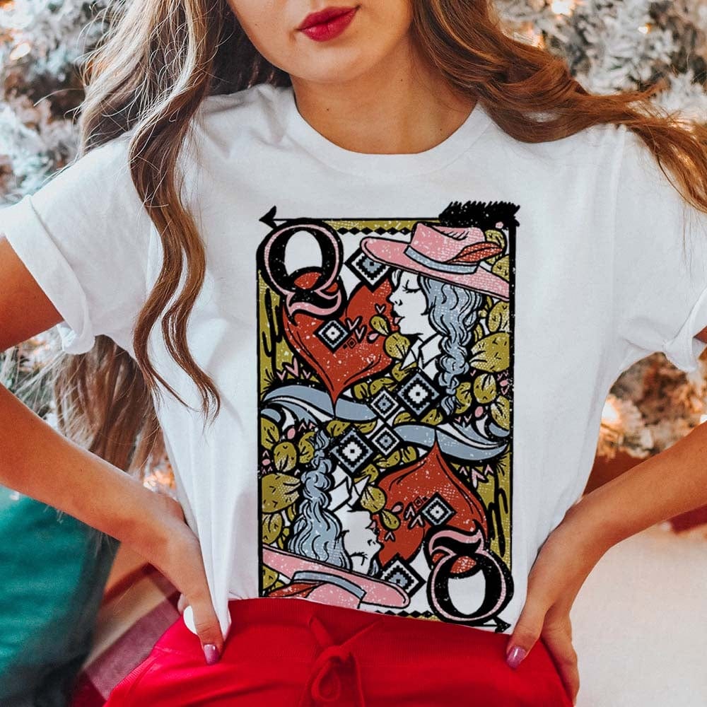 Model is wearing a white graphic tee that has a Queen of Hearts playing card pictured on the front. Model has it paired with red pants.