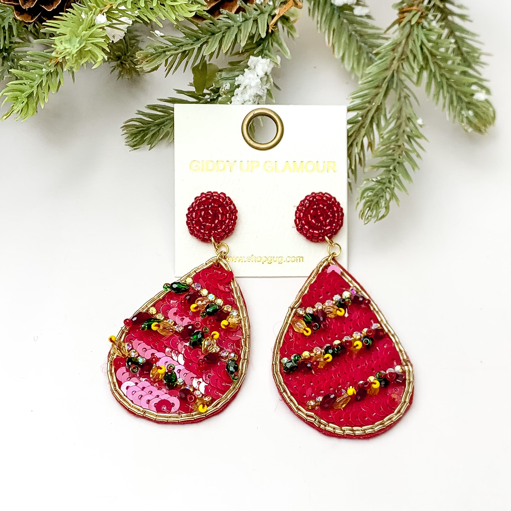 Red sequin beaded teardrop earring with ab crystals and beaded tassels. These earrings are pictured on a white background with pine trees at the top of the picture. 