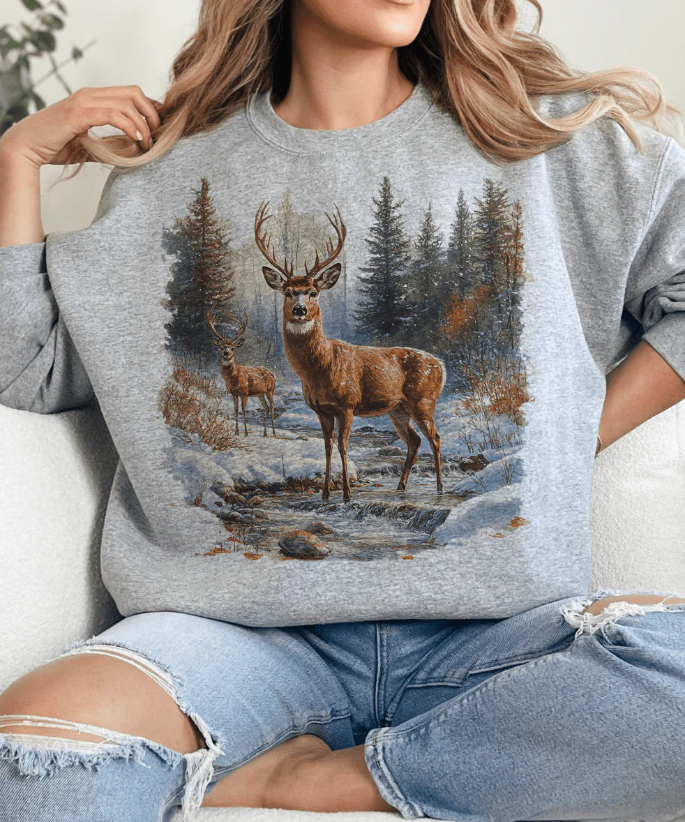 Person wearing a gray sweatshirt with a deer graphic in a forest setting