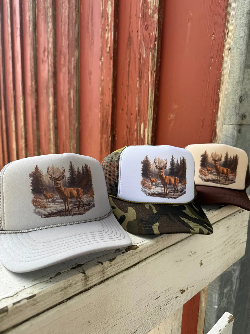 Three hats with deer designs on a wooden surface against a rustic background