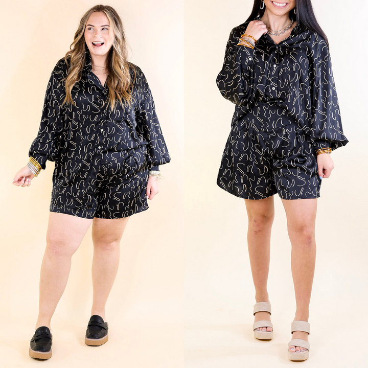 Two models wearing black satin shorts with an ivory swirl print.