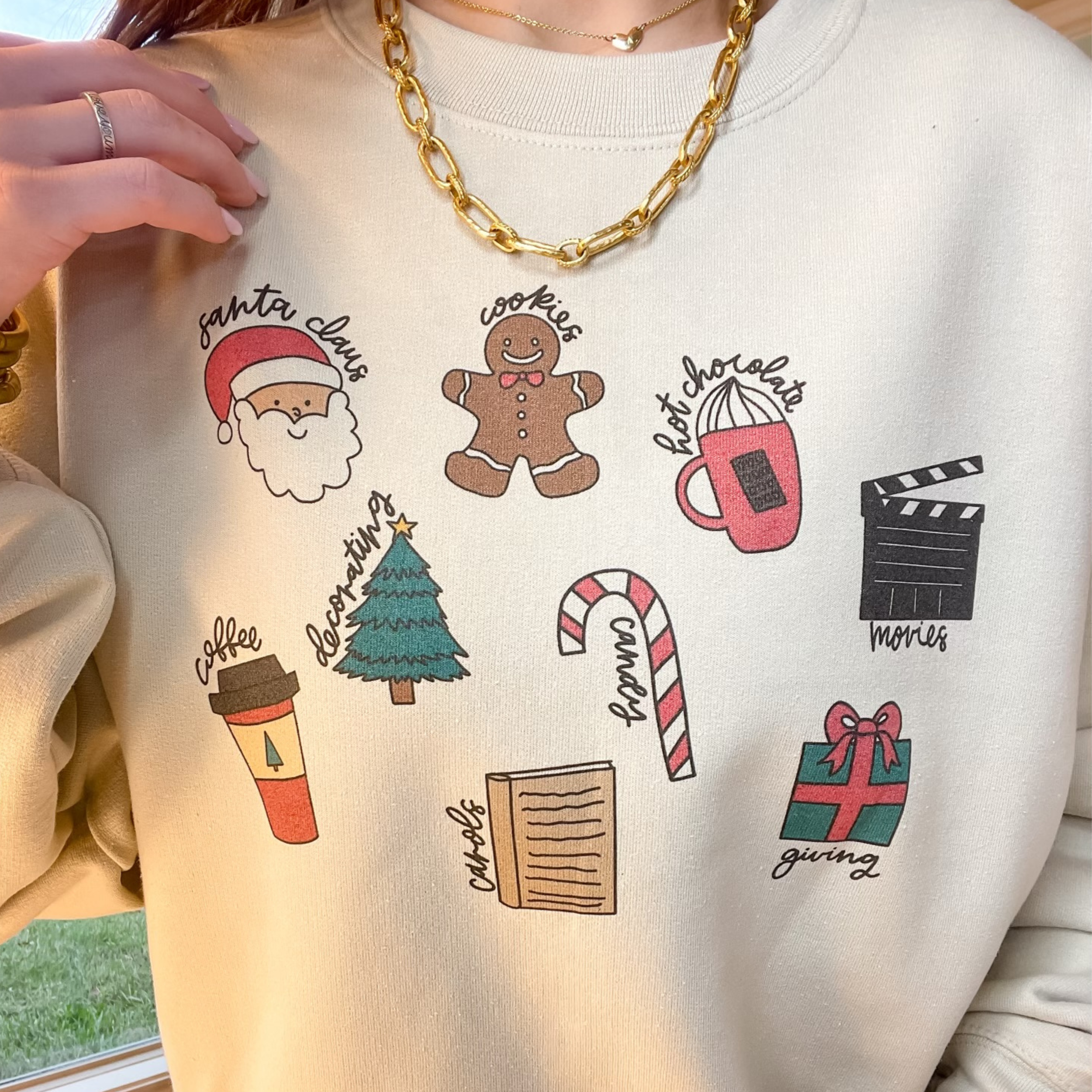 Photo features a cream sweatshirt with a variety of different Christmas icons.  