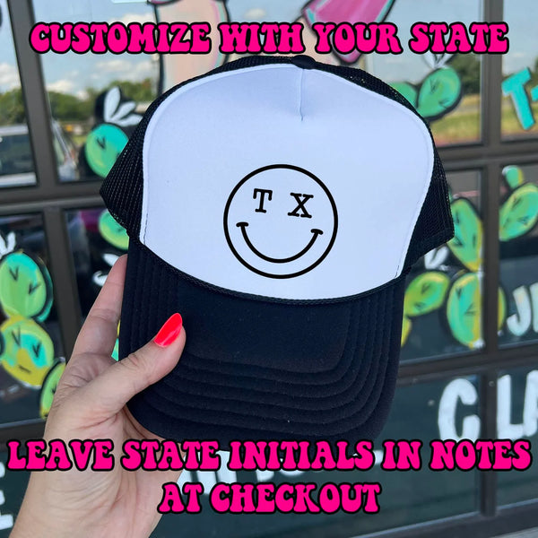 In the picture is a black and white trucker hat with a Texas smiley face. 