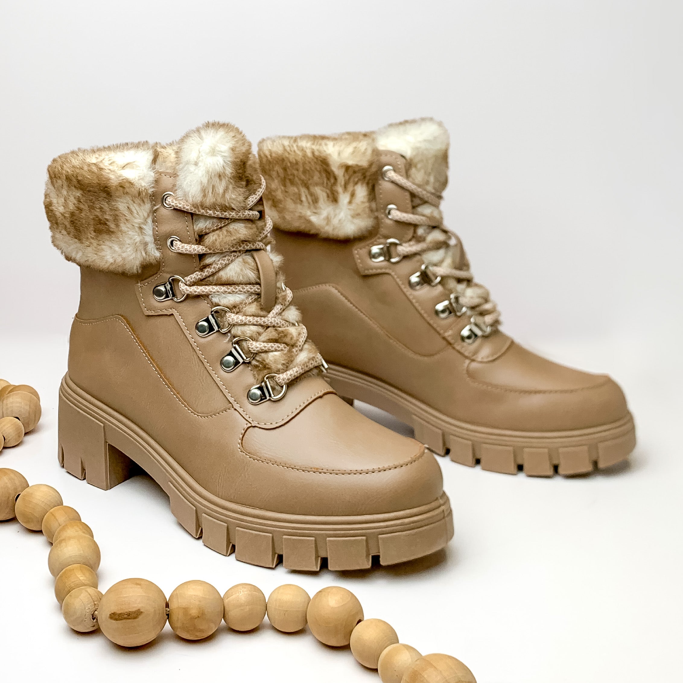 Faux fur lined lace up chunky heel booties in taupe. Pictured on white background with light tan beads.