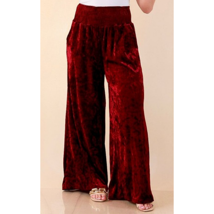 Full length image of a woman wearing the Velvet Hour Smocked Waist Crushed Velvet Wide Leg Pants in Maroon