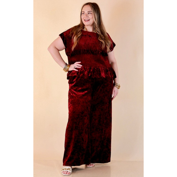 Full length image of a woman wearing the Velvet Hour Smocked Crushed Velvet Cap Sleeve Peplum Top in Maroon