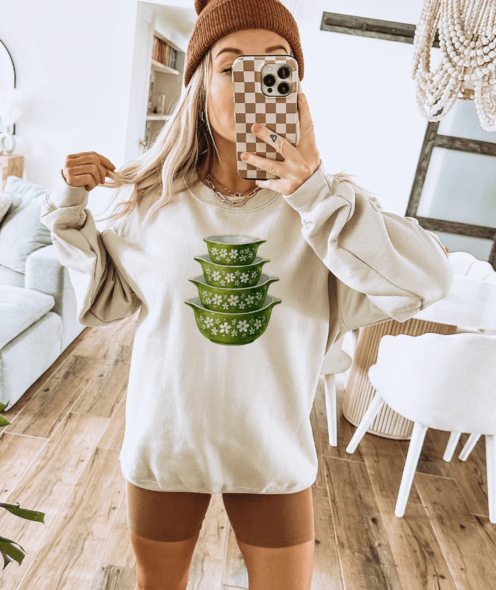 Vintage green Pyrex inspired bowl stack graphic tee printed on a cream shirt for vintage kitchen and thrift lovers.