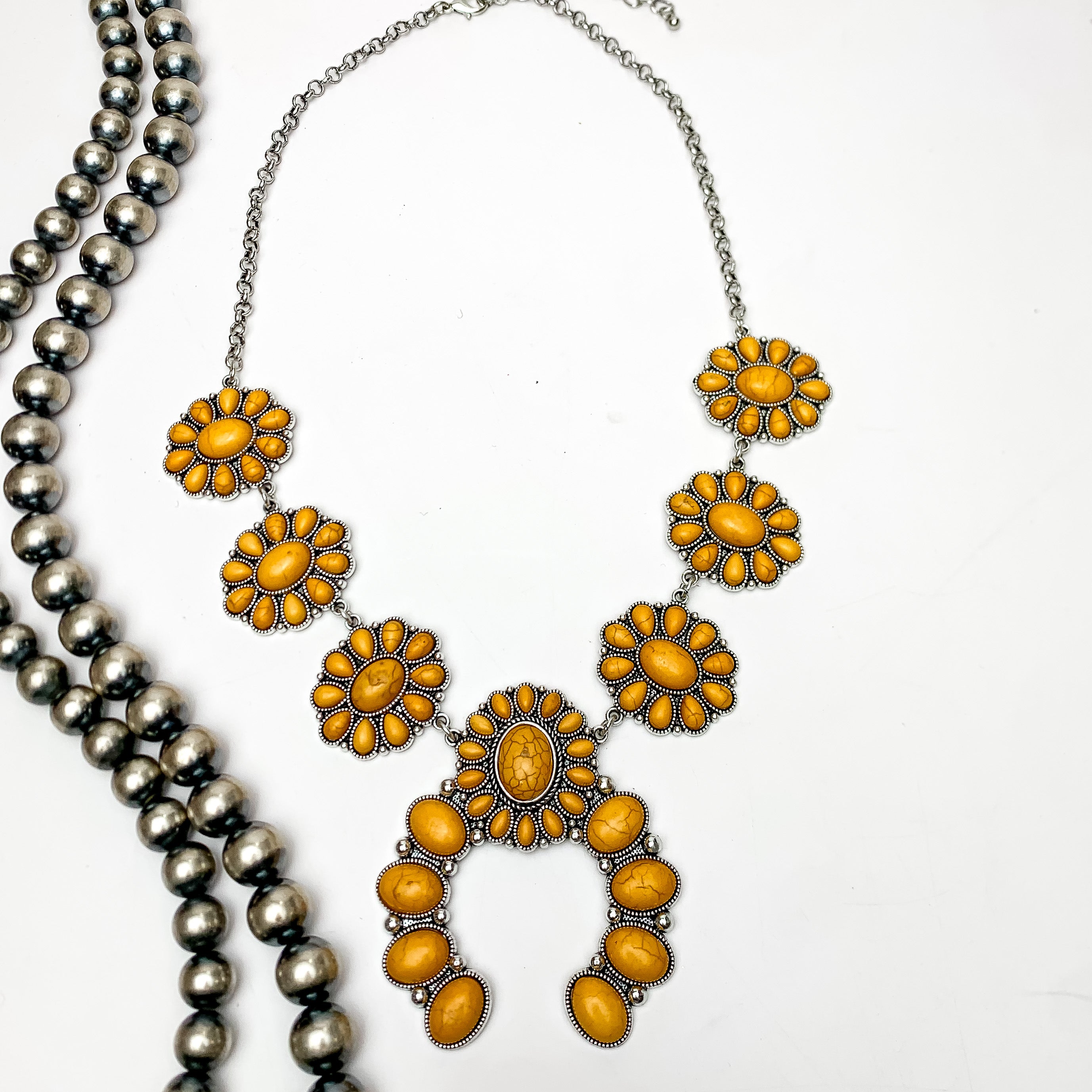 The Western Way Squash Blossom Necklace in Yellow. This necklace is pictured on a white background with beads on the left side.