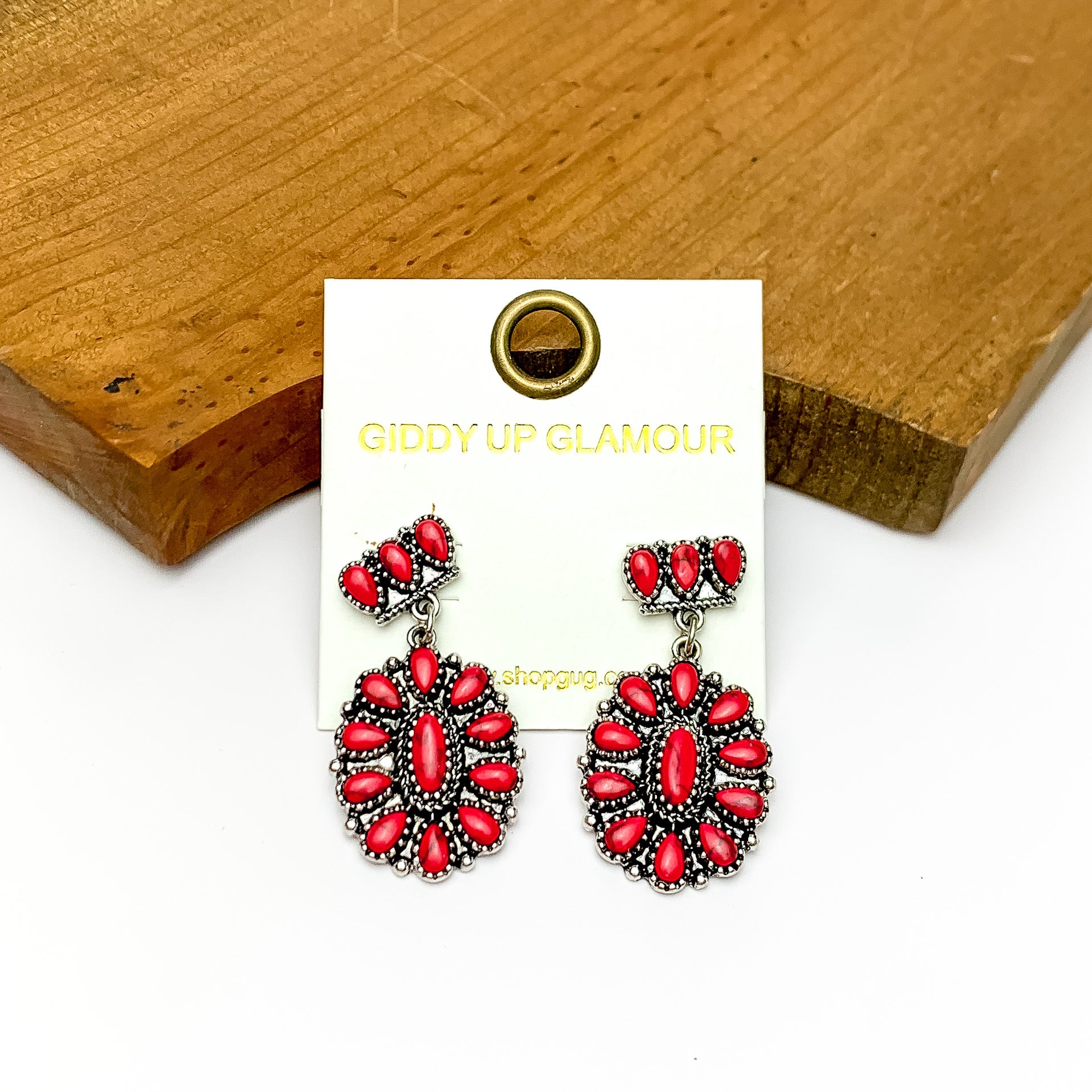 Red marble and silver flower drop earrings. Pictured on a white background with a piece of wood at the top.