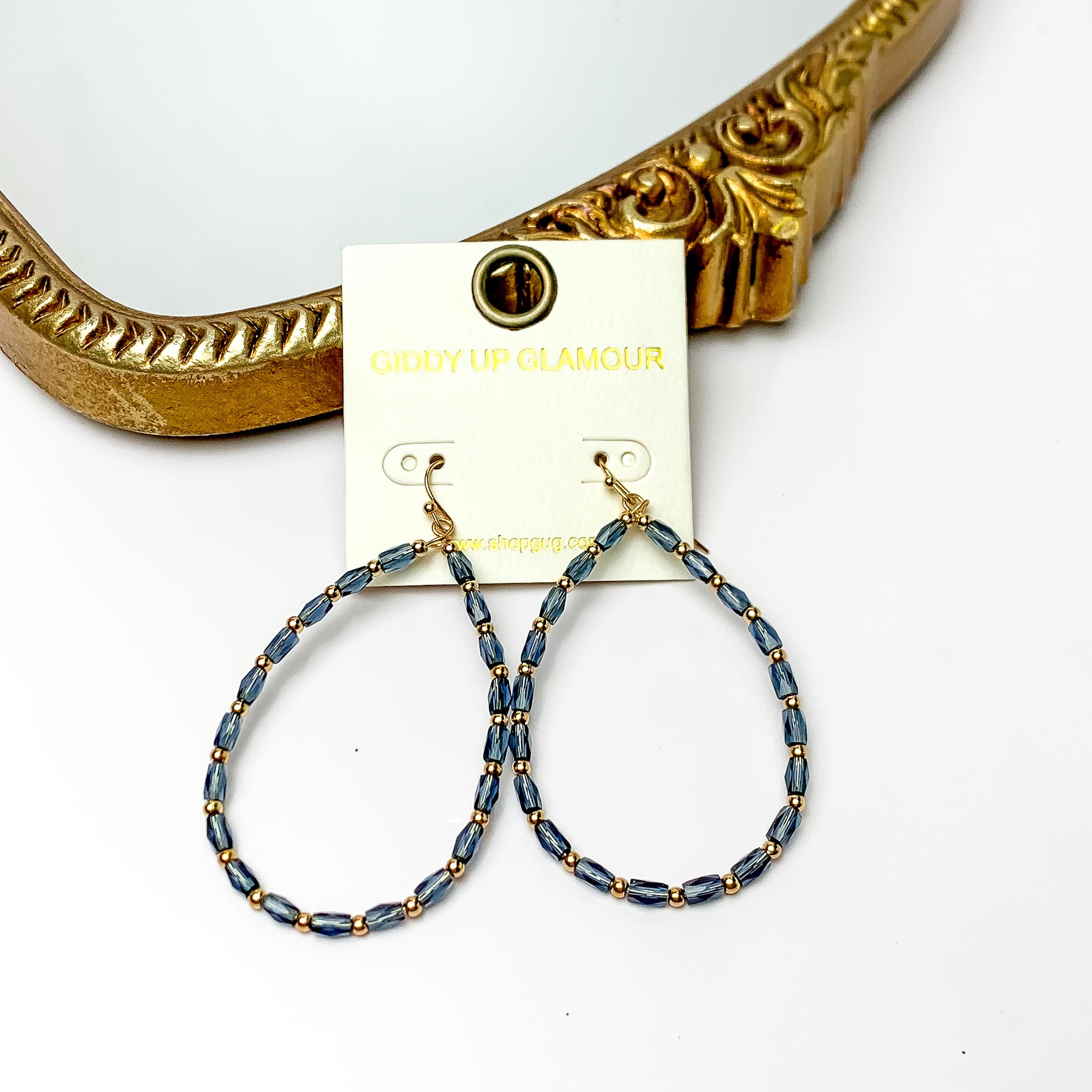 Midnight blue open dangle earrings with a gold tone feature. Pictured on a white background with a gold frame. 