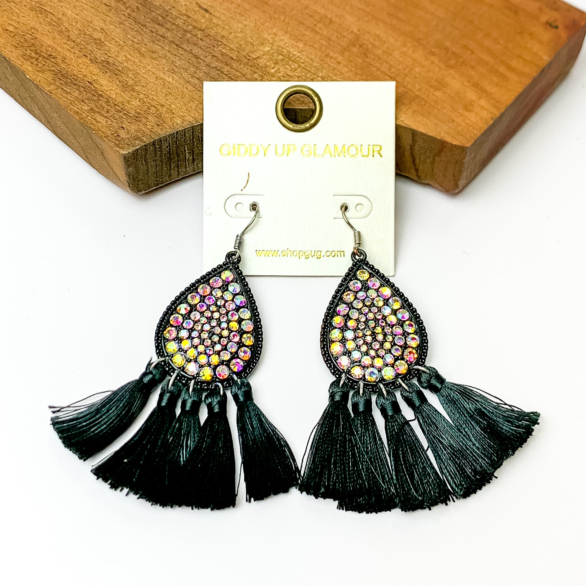 AB crystal drop earrings with black tassels. Pictured on a white background and a wood piece at the top.