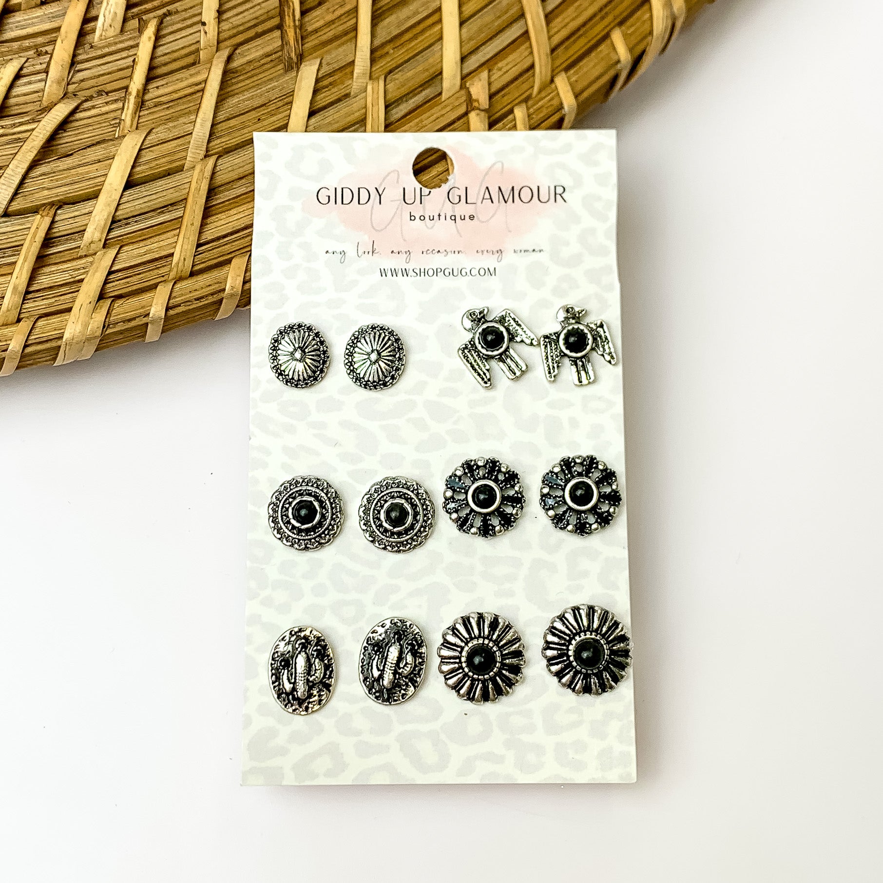 Set of six black and silver stud earrings. Pictured with a white background and a wood like decoration in the top left.
