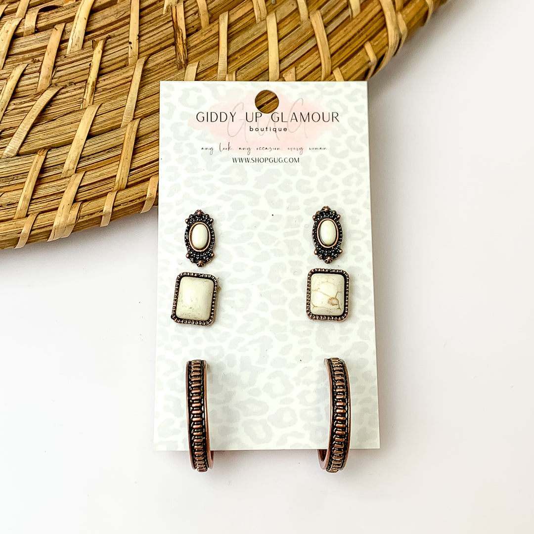 Set of three cream colored and copper tone designed stud earrings. Pictured with a white background and wood like décor in the top left.