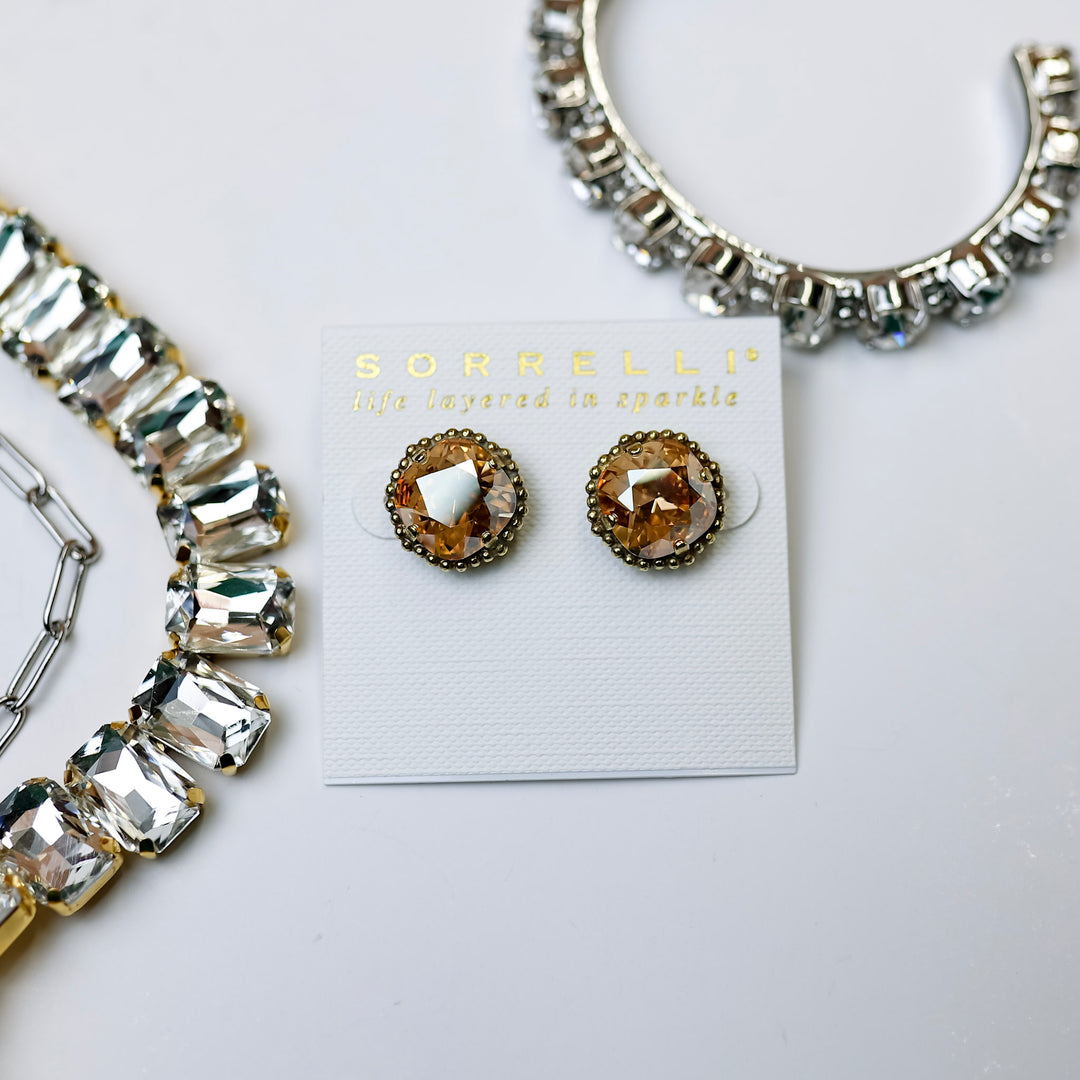 A pair of dark champagne cushion cut crystal earrings in a bronze-tone setting. Pictured on a white background with crystal earrings.