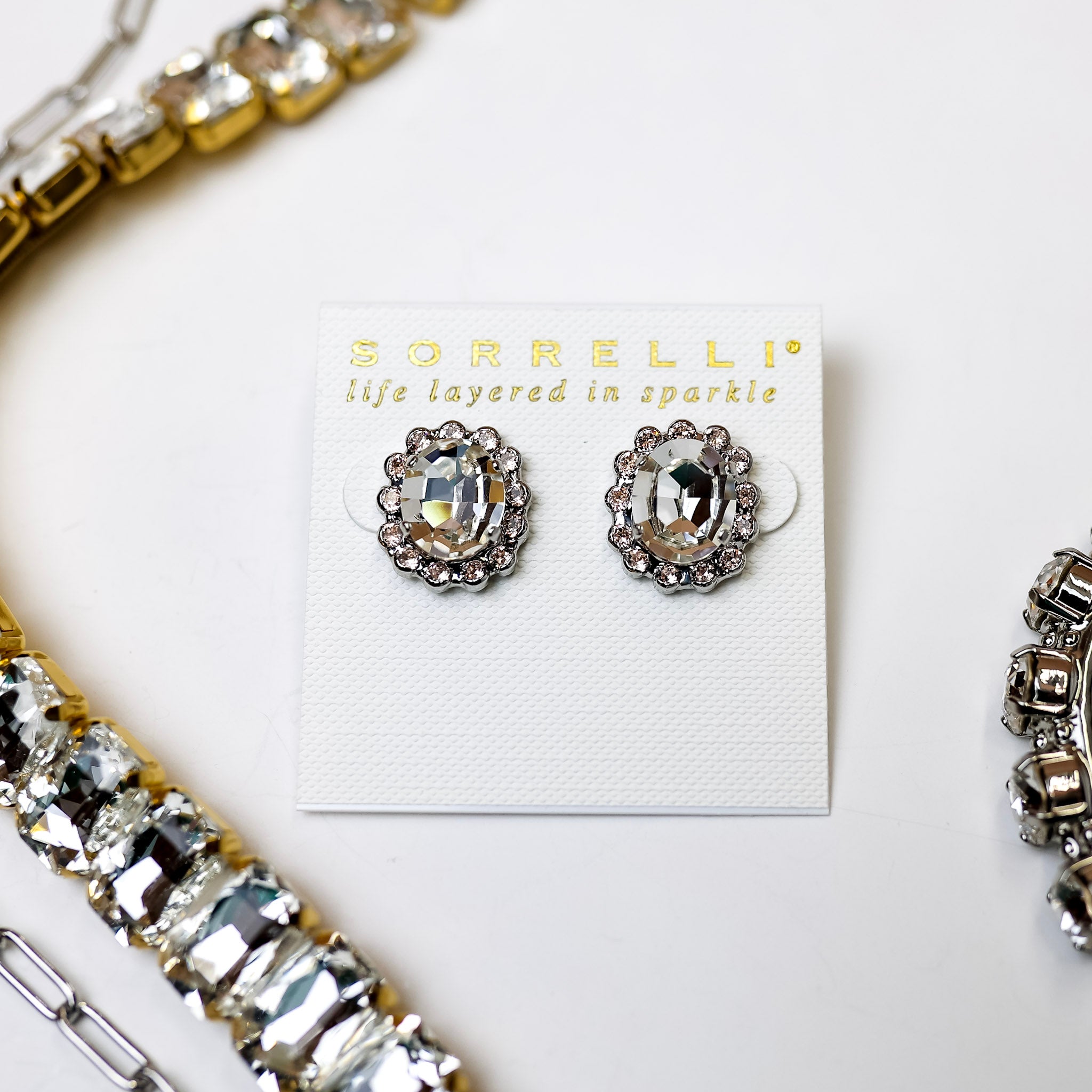 A pair of round crystal earrings with small crystal outline. Pictured on a white background with crystal necklaces.
