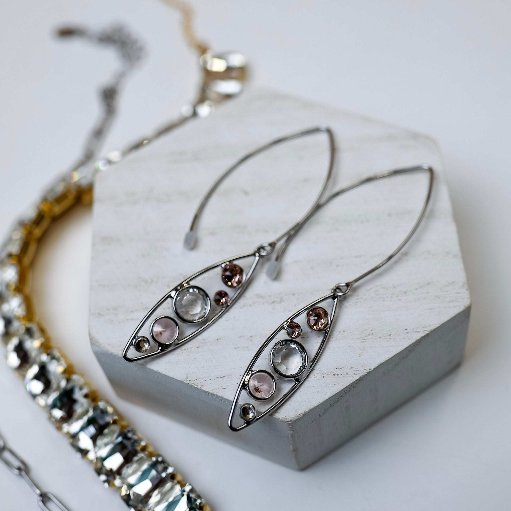 A pair of silver-tone dangle earrings with an oval outline and crystals.