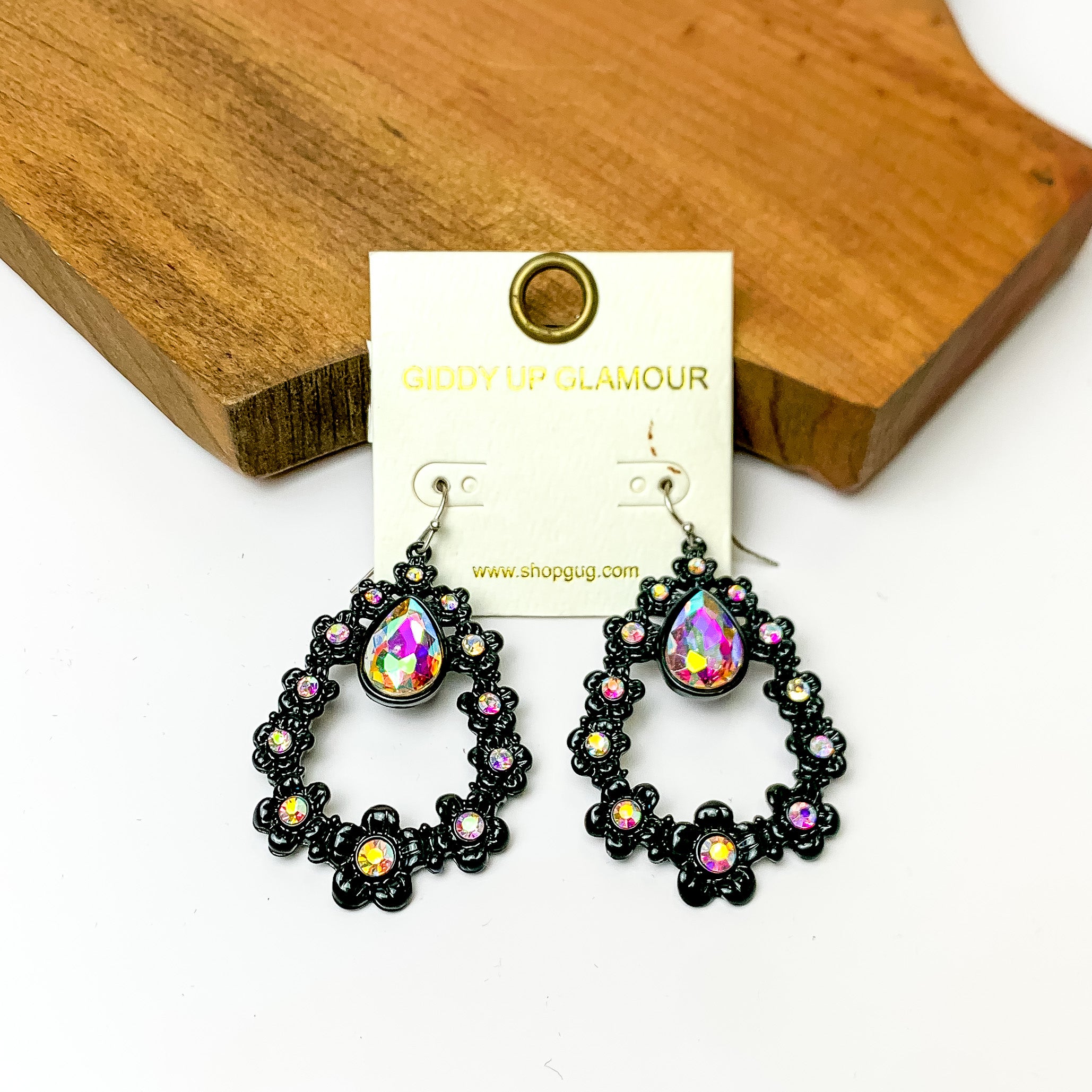 Black open drop earrings with ab crystals and connecting flowers. Pictured on a white background with a wood piece at the top.