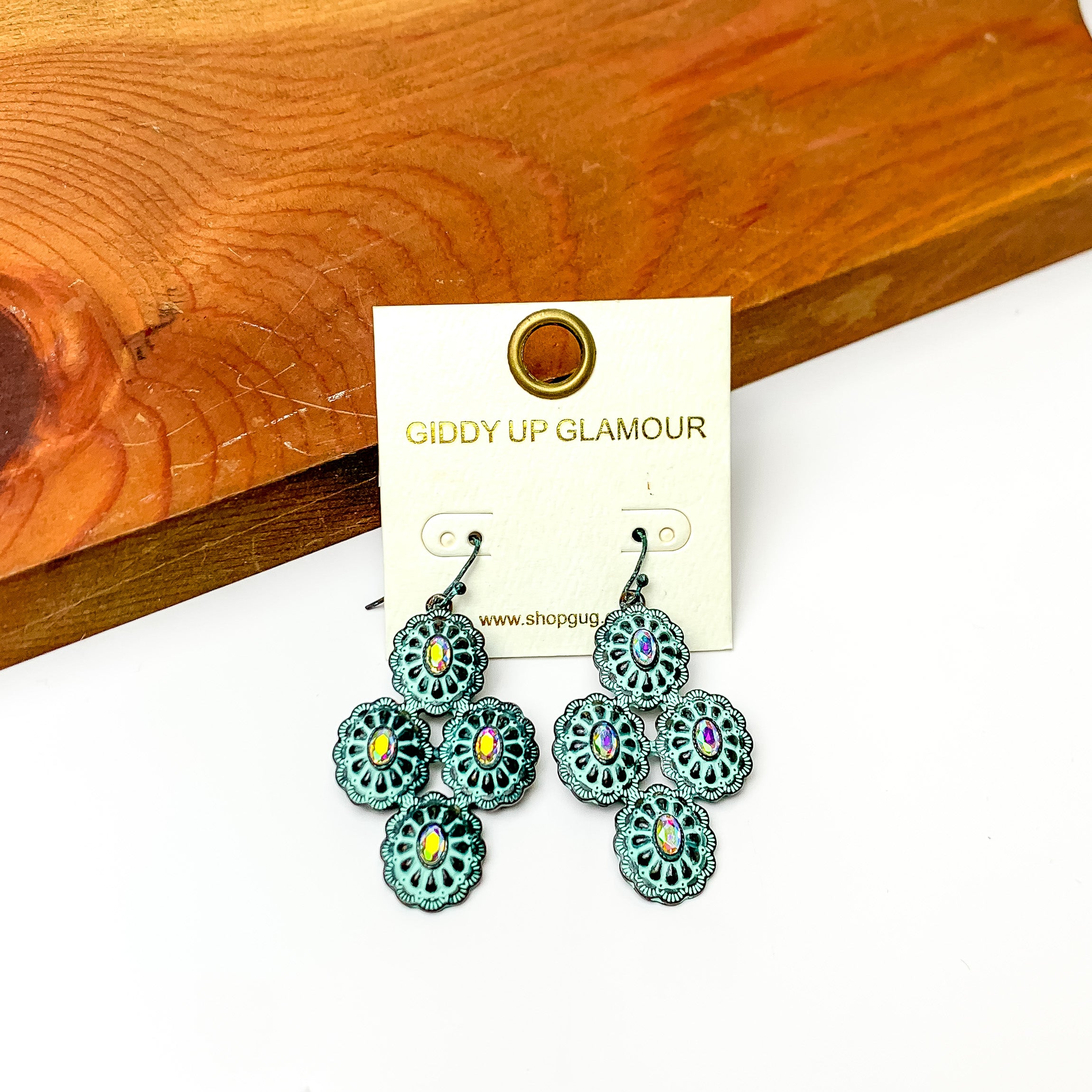 Turquoise style dangle earrings with ab crystals. Pictured on a white background with wood at the top.