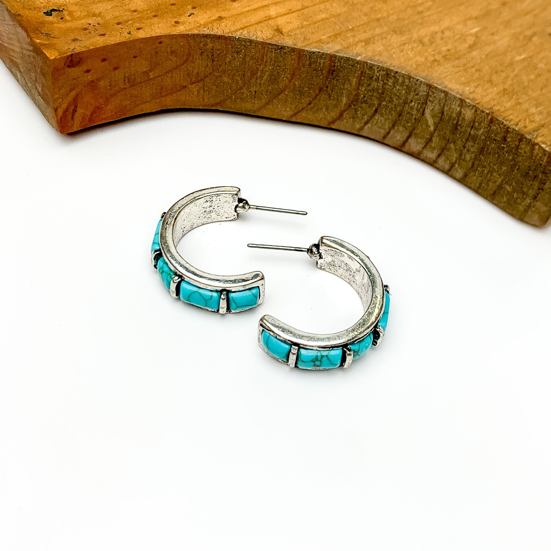 Turquois and silver tone medium size hoops. Pictured on a white background with a wood piece at the top