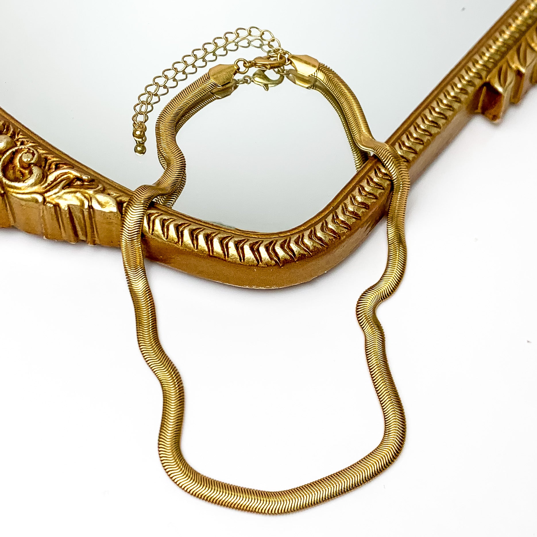 Gold tone classic chain necklace. Pictured on a white background with a gold frame through the middle.