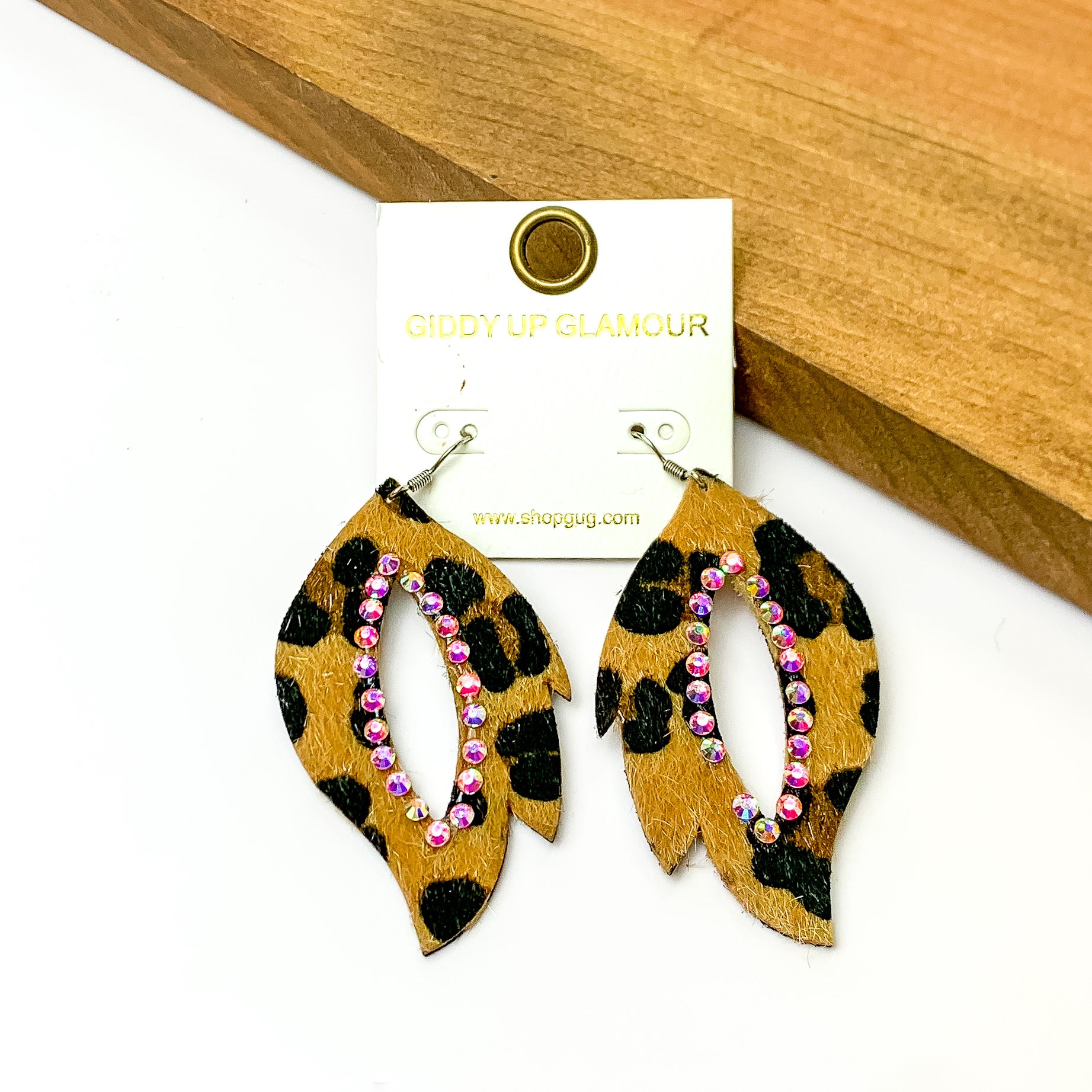 Open drop cheetah print earrings with AB crystals around the inside. Pictured on a white background with a wood piece in the top right corner.