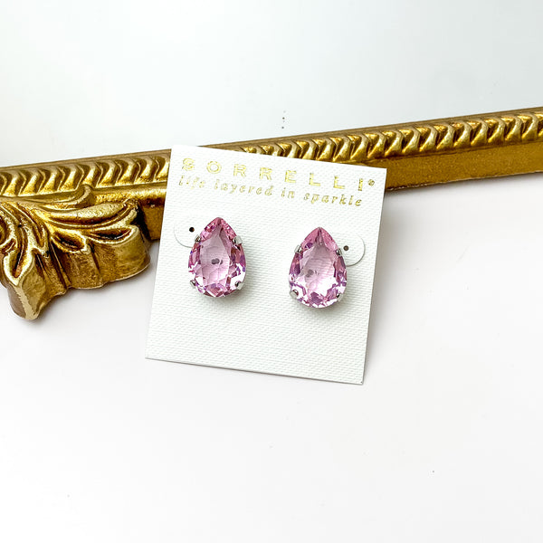 Single light pink crystal stud earrings with a silver backing. Pictured on a white background with a gold figure through the middle