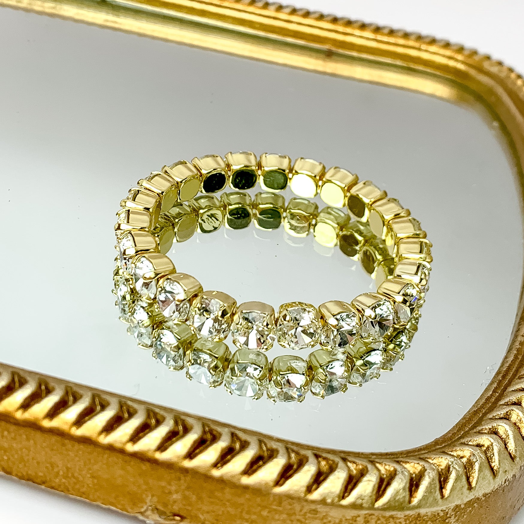 Single crystal layered bracelet stretchy to fit most wrists with gold undertones. Pictured on a mirror with a gold frame