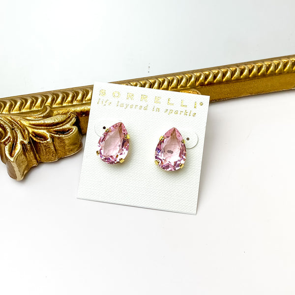 Single pink crystal stud earrings with a gold backing. Pictured on a white background with a gold figure through the middle