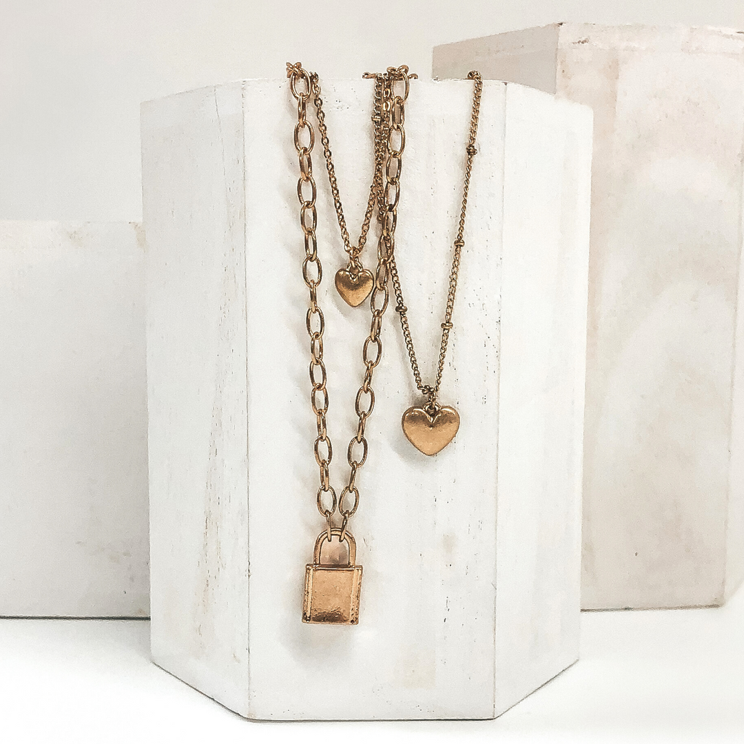 multiple gold chained necklace with 2 heart charms and lock pendant