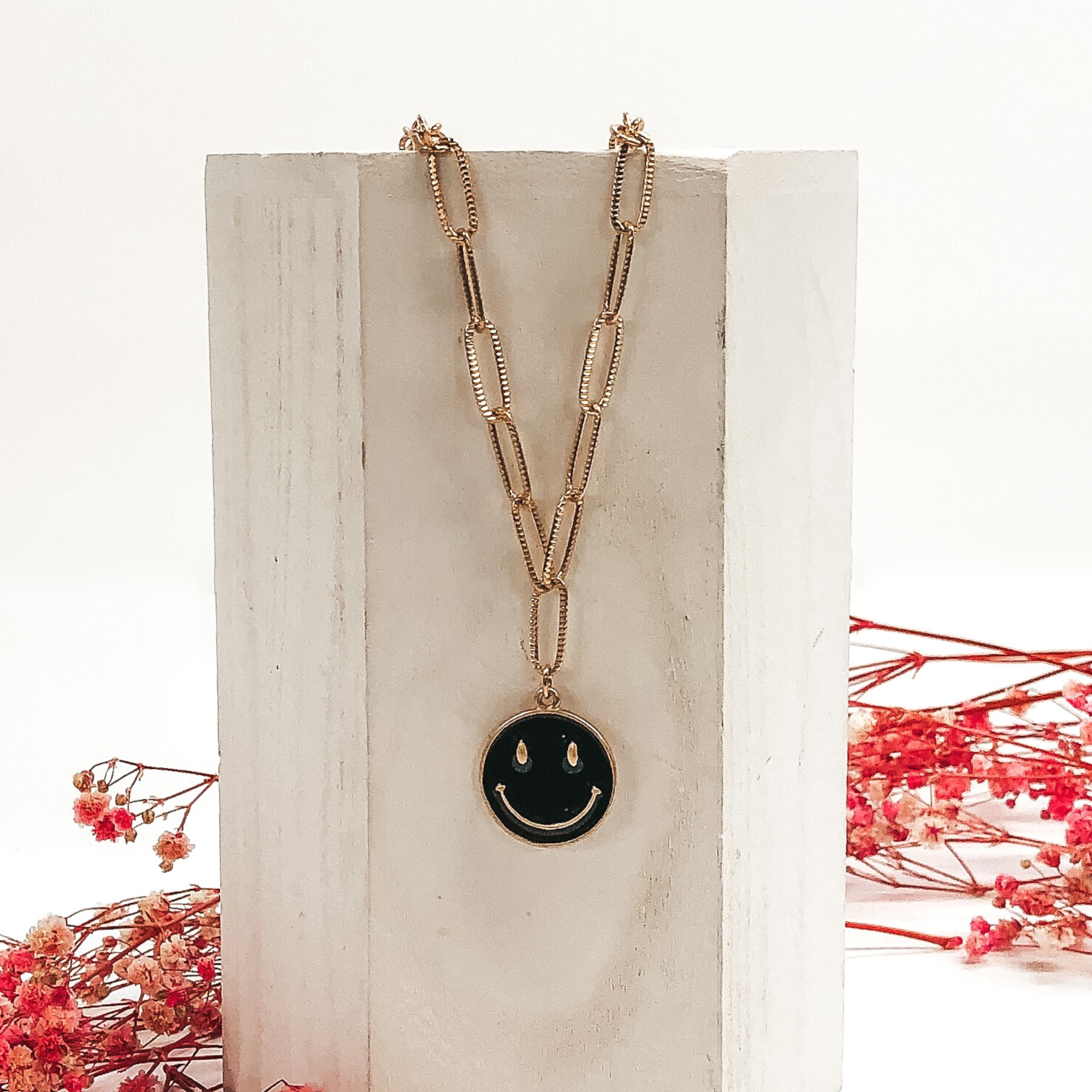 gold necklace with black smiley face