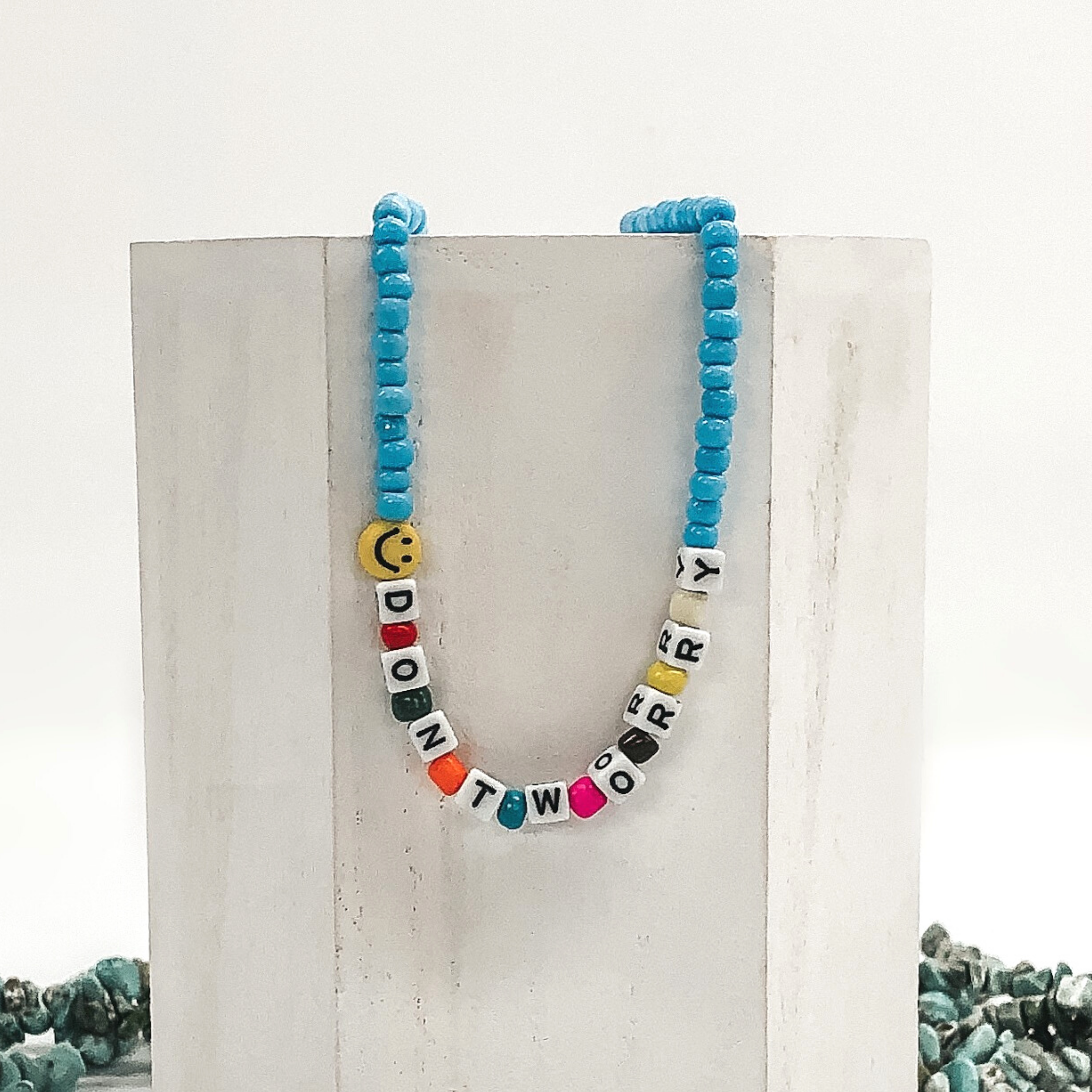 light blue beaded necklace with letter beads that spell out don't worry and smiley face bead