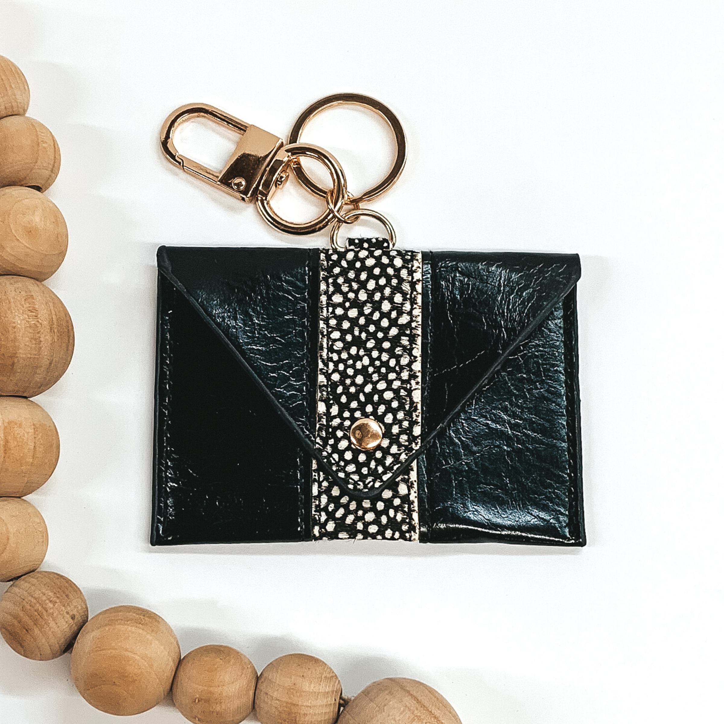 black genuine leather rectangle wallet with hair on hide dotted stripe and snap closure that includes a gold key ring on white background